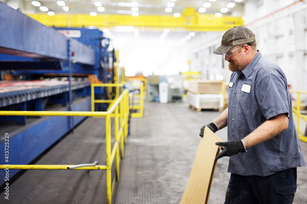 Smiling worker holding metal sheets while working in Steel Industry Factory Smiling worker holding metal sheets while working in Steel Industry Factory