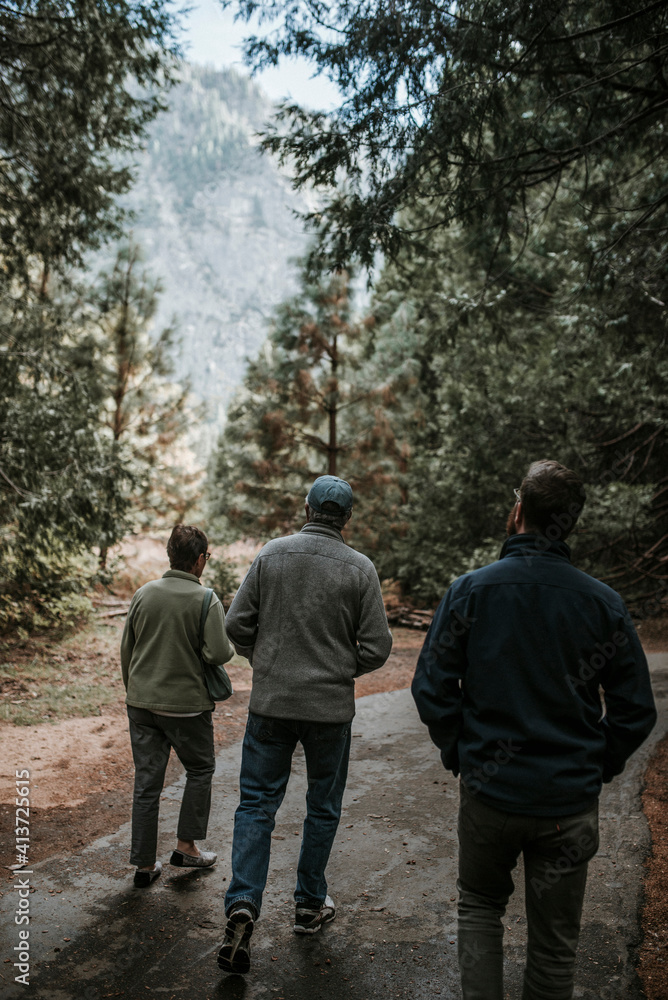 Rear view of friends walking on footpath amidst forest at Yosemite National Park Rear view of friends walking on footpath amidst forest at Yosemite National Park