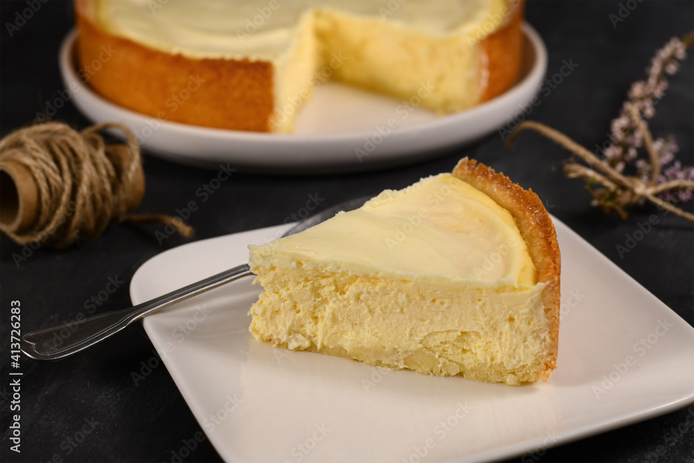 Slice of traditional New York cheesecake with cream cheese and sour cream layer on white plate Slice of traditional New York cheesecake with cream cheese and sour cream layer on white plate