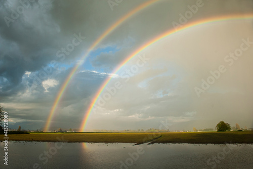 Scenic view of double rainbows against cloudy sky