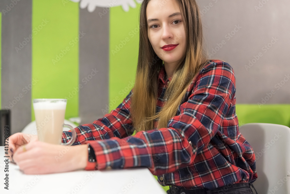 Young beautiful girl is drinking coffee in a cafe in the evening. Young beautiful girl is drinking coffee in a cafe in the evening.