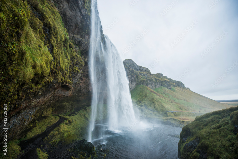 Majestic view of waterfall by mountains Majestic view of waterfall by mountains