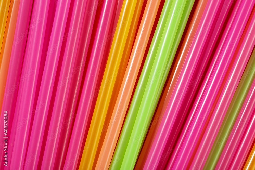 Colored tubules for juice and cocktails on orange background. Space for text.