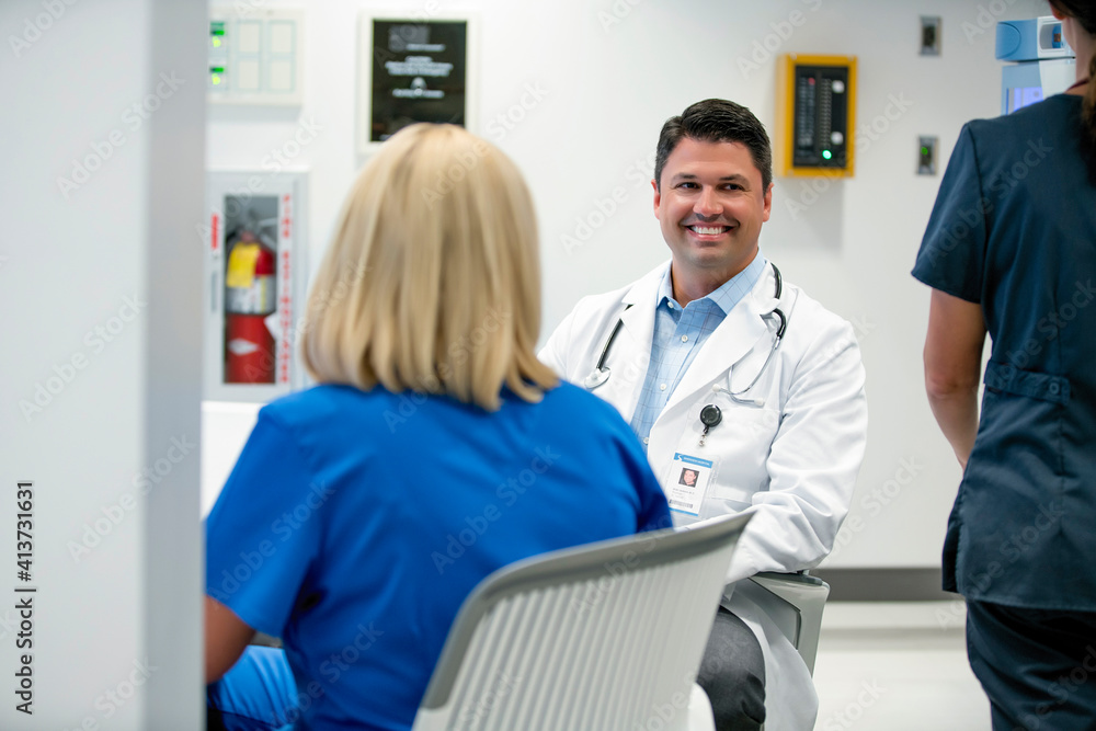 Happy doctor looking away while female colleagues in foreground Happy doctor looking away while female colleagues in foreground