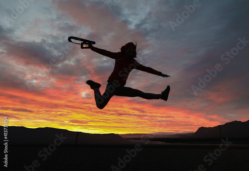 Wallpaper Mural Excited hiker holding camera while jumping against dramatic sky Torontodigital.ca