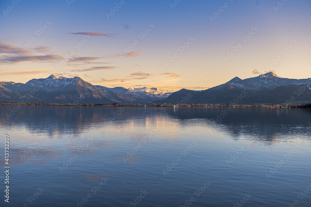 Calm lake surrounded by mountains during sunset