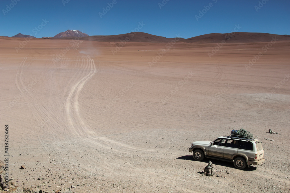 High angle view of off-road vehicle moving on landscape against clear blue sky during sunny day High angle view of off-road vehicle moving on landscape against clear blue sky during sunny day