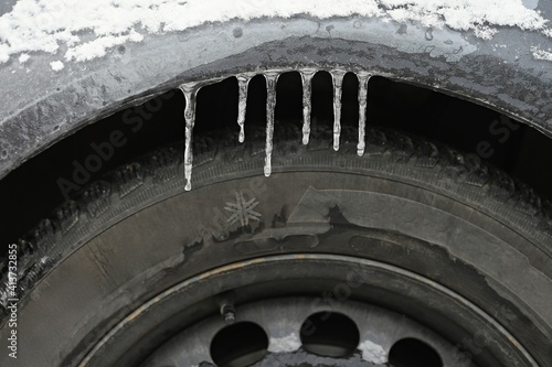 Frozen car with a tire. Beautiful icicles . Concept for winter and dangerous traffic on the road.