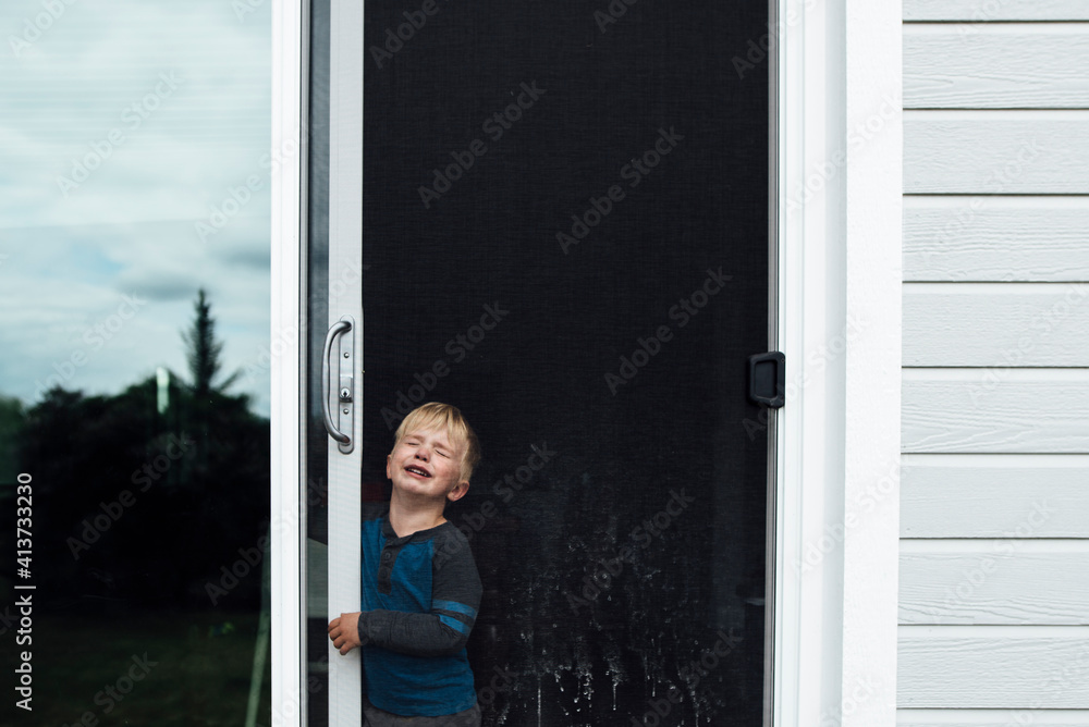 Boy crying while standing by window