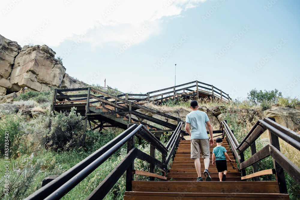 Rear view of father with son moving up on steps against sky Rear view of father with son moving up on steps against sky