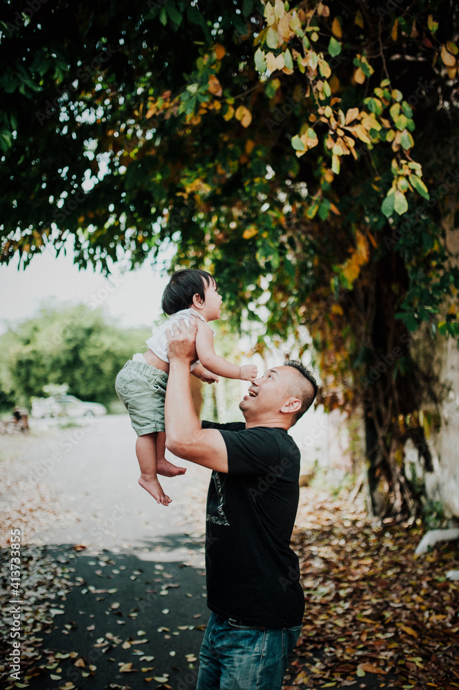 Side view of happy father picking up son while standing on street Side view of happy father picking up son while standing on street