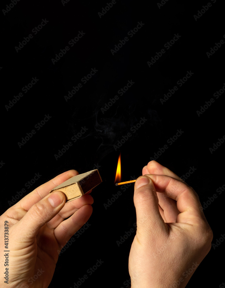 Hands holds a burning match on a black background. A wooden match burns in the hands of a macro. Igniting a match on a box. Smoke from a match. Flash Hands holds a burning match on a black background. A wooden match burns in the hands of a macro. Igniting a match on a box. Smoke from a match. Flash