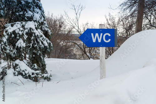 Blue toilet plate in a snowy city park Indicates the direction to the WC © Виталий Борковский