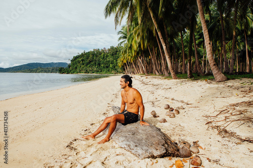 Shirtless man looking at view while sitting on wood photo