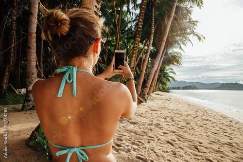 Rear view of young woman using smart phone at beach photo