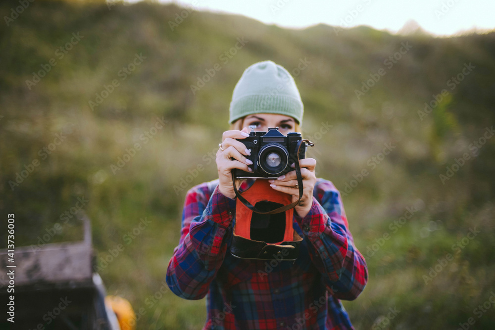 Young woman photographing with camera while standing on field Young woman photographing with camera while standing on field