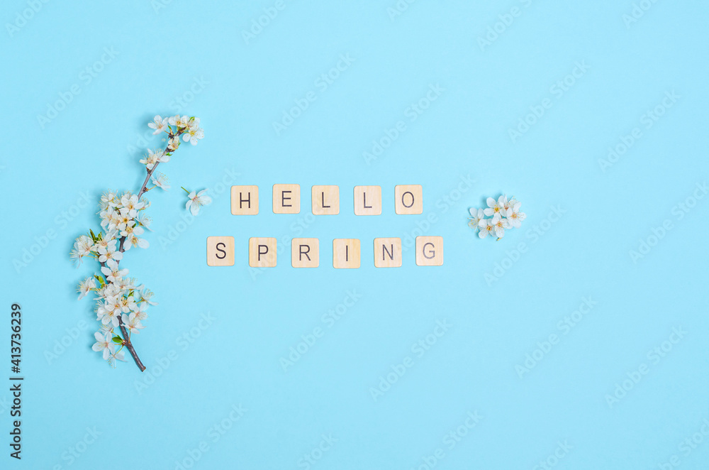 Naklejka premium Blooming cherry branches with white flowers, text hello spring on a blue background