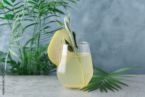 Pear drink with sage. Fruit lemonade summer, refreshing drink on green plants background 