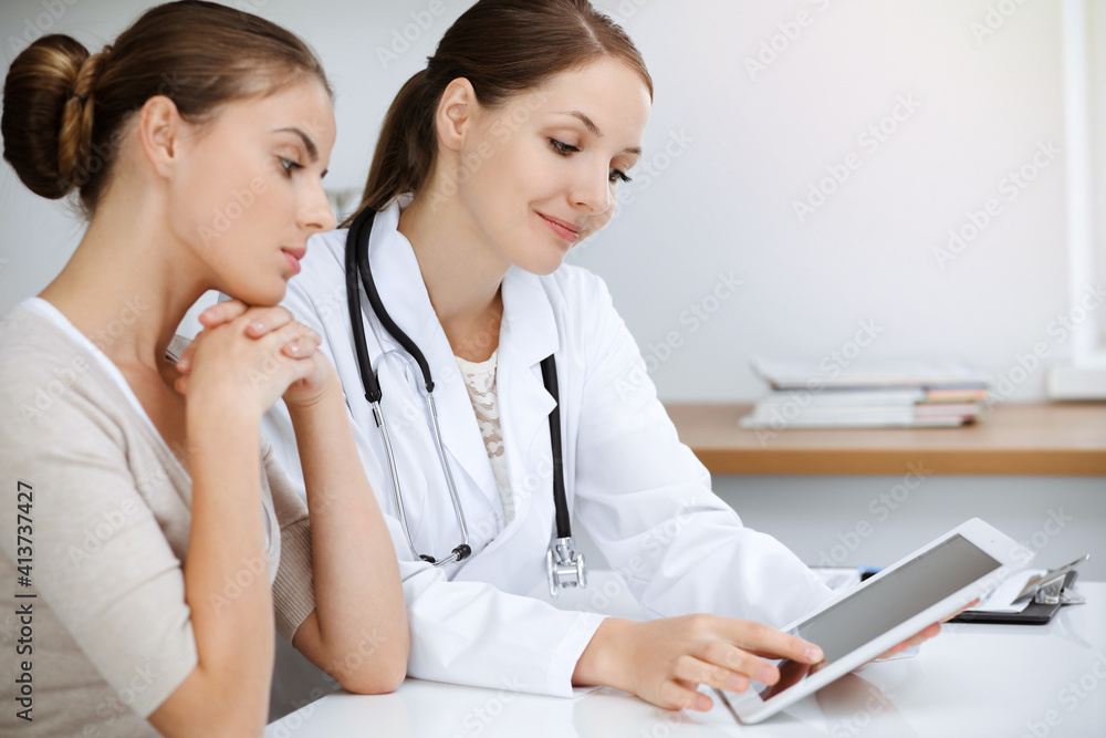 Doctor and patient are sitting and discussing health examination results while using tablet computer. Health care, medicine and good news concepts Doctor and patient are sitting and discussing health examination results while using tablet computer. Health care, medicine and good news concepts