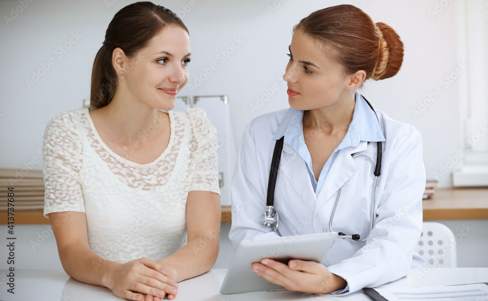 Doctor and patient are sitting and discussing health examination results while using tablet computer. Health care, medicine and good news concepts Doctor and patient are sitting and discussing health examination results while using tablet computer. Health care, medicine and good news concepts