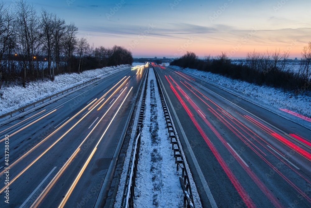 Fototapeta premium Befahrene Autobahn mit Langzeitbelichtung aufgenommen mitten in Deutschland bei Sonnenuntergang.