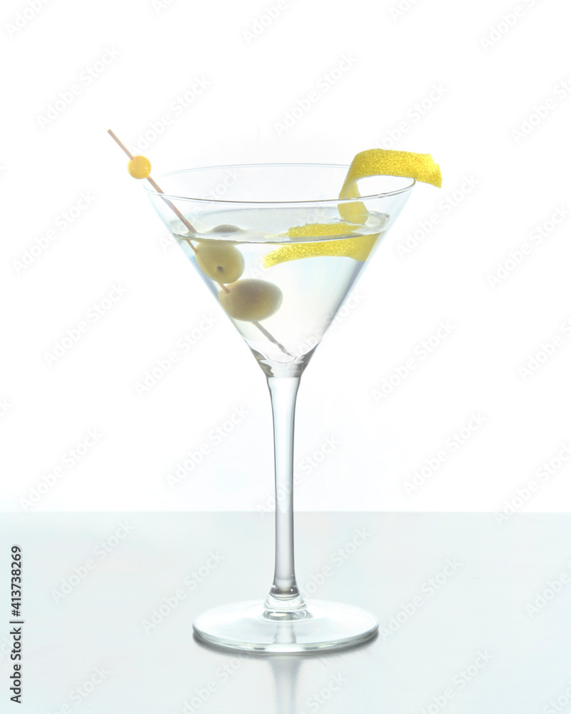Martini mixed drink with lemon peel garnish and olives on a white background.