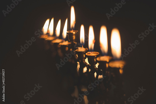 Close-up of Hanukkah Menorah candles glowing in darkroom