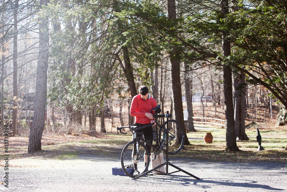 Athlete adjusting bicycle on road during sunny day Athlete adjusting bicycle on road during sunny day