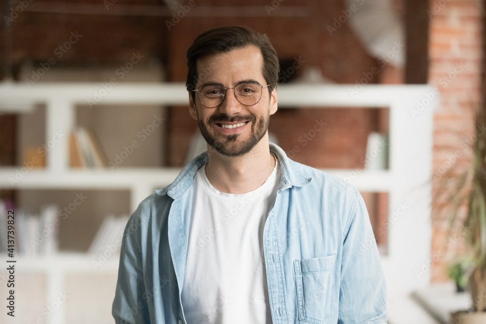 Portrait of smiling millennial Caucasian male tutor or coach wear glasses pose in modern office of classroom. Headshot of happy young man employee satisfied with work job. Employment concept. Portrait of smiling millennial Caucasian male tutor or coach wear glasses pose in modern office of classroom. Headshot of happy young man employee satisfied with work job. Employment concept.