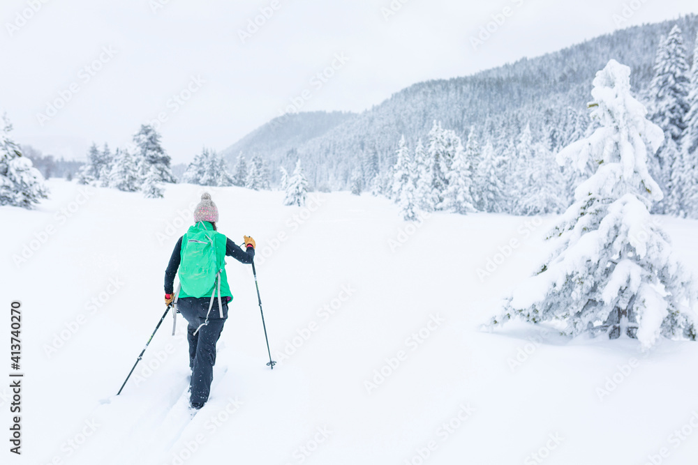Rear view of female hiker hiking on snow covered field Rear view of female hiker hiking on snow covered field