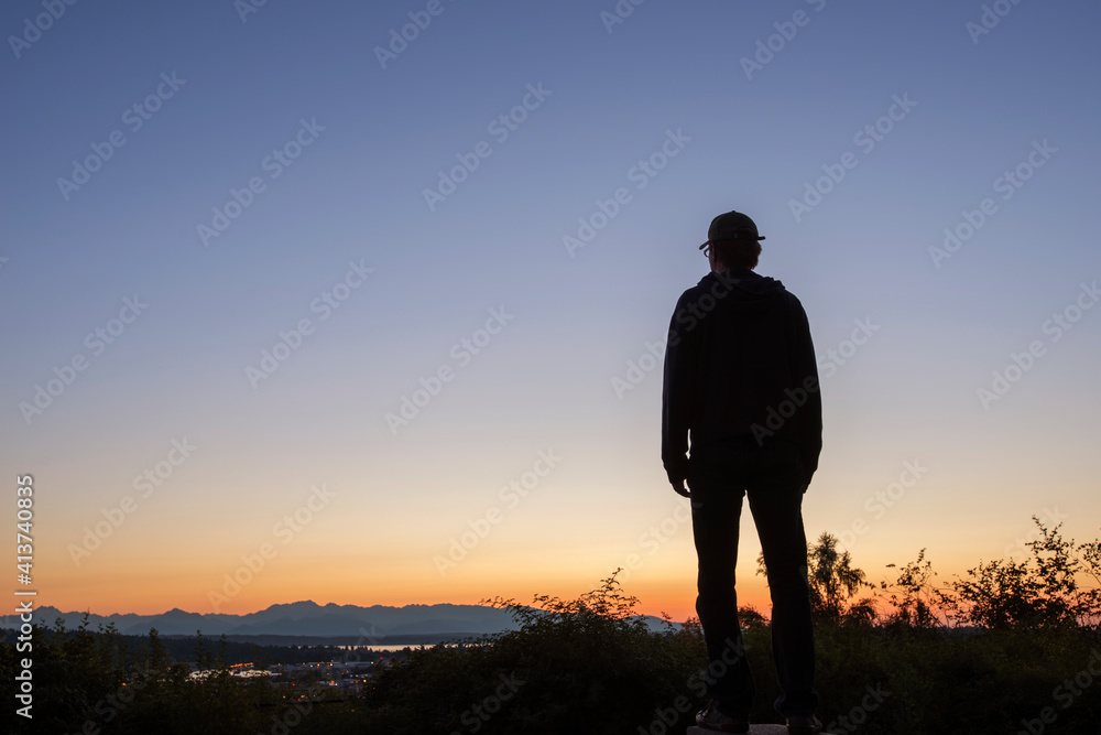 Silhouette man looking at view while standing on mountain against clear sky during sunset Silhouette man looking at view while standing on mountain against clear sky during sunset