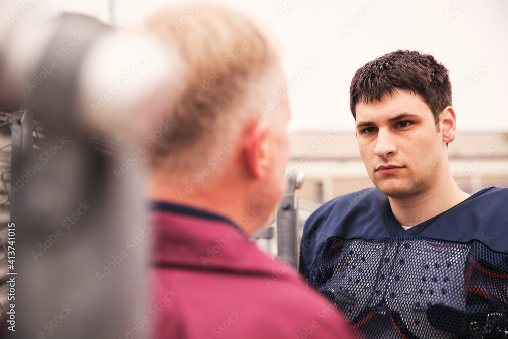 Coach discussing with American football player at stadium Coach discussing with American football player at stadium