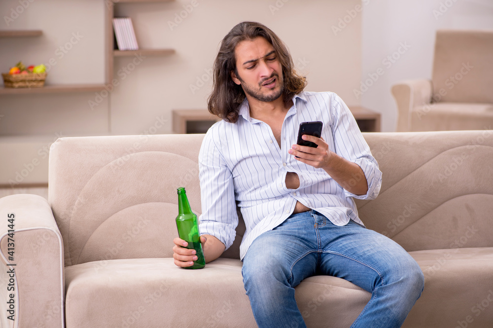 Obraz premium Young man drinking alcohol at home