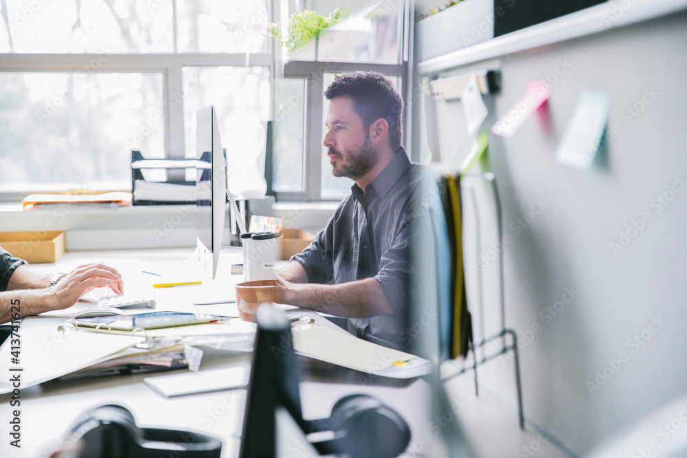 Businessman reflecting on computer monitor in office Businessman reflecting on computer monitor in office
