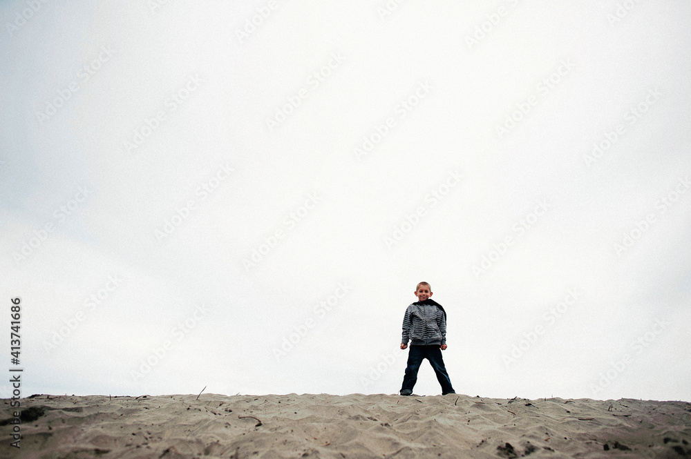 Portrait of smiling boy standing on sand at beach against sky Portrait of smiling boy standing on sand at beach against sky