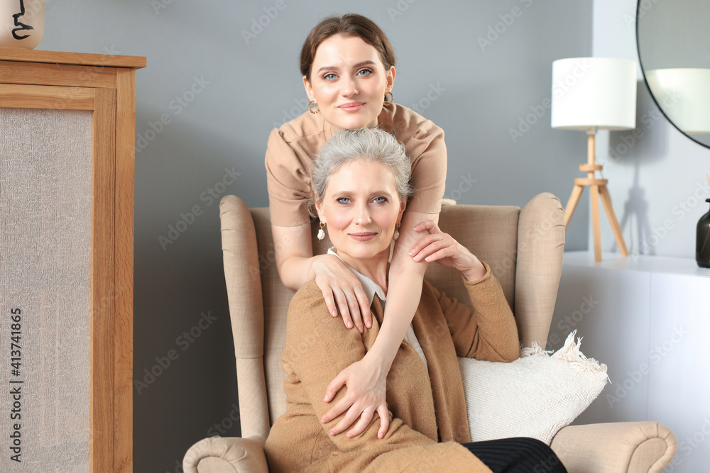 Elderly middle mother sitting in a chair and her daughter are hugging, looking at camera, trusted relations. Elderly middle mother sitting in a chair and her daughter are hugging, looking at camera, trusted relations.