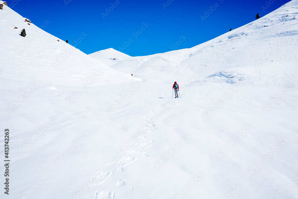 Mid distance view of hiker hiking on snow covered mountain at Joshua Tree National Park Mid distance view of hiker hiking on snow covered mountain at Joshua Tree National Park