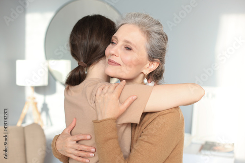 Portrait of old mother and mature daughter hugging at home. Happy trusted relations. Family concept.