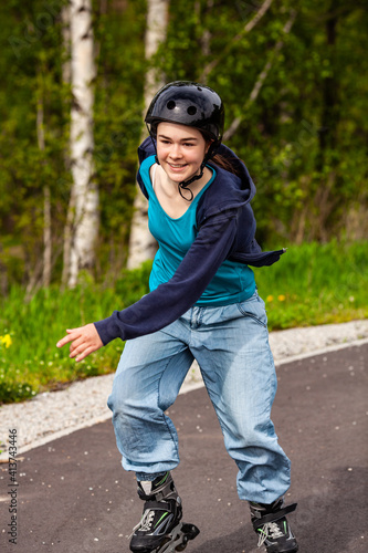 Teenage girl rollerblading against blue sky 