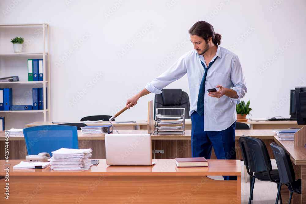 Young male furious employee holding nun-chucks in the office Young male furious employee holding nun-chucks in the office