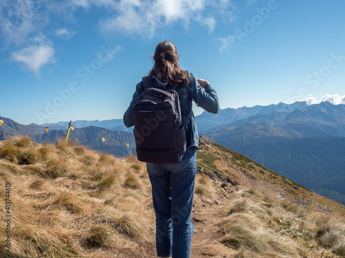 Hiking in the mountains, a young female tourist with a backpack is walking along