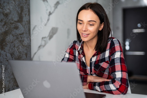 Beautiful young woman working on her laptop in her home office. photo