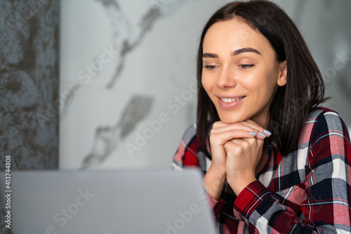 Beautiful young woman working on her laptop in her home office.