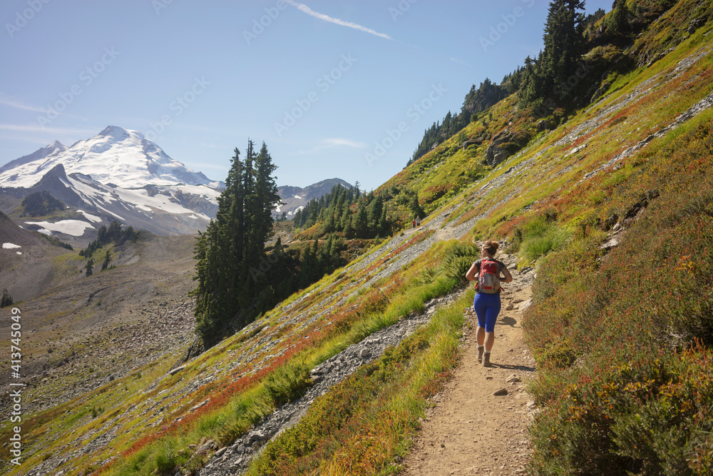 Rear view of female hiker hiking on mountain against sky Rear view of female hiker hiking on mountain against sky