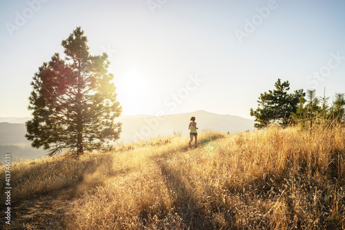 Full length woman jogging on mountain against sky during sunny day