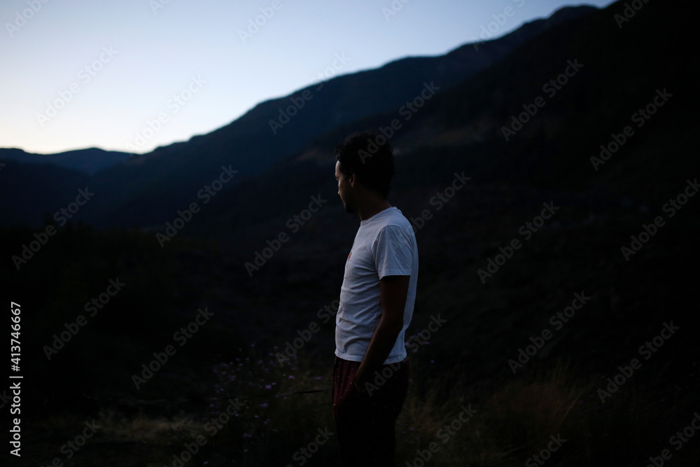 Side view of man standing by mountain against sky during sunset Side view of man standing by mountain against sky during sunset