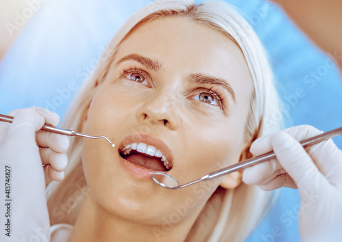 Smiling blonde woman examined by dentist at dental clinic. Healthy teeth in medicine concept