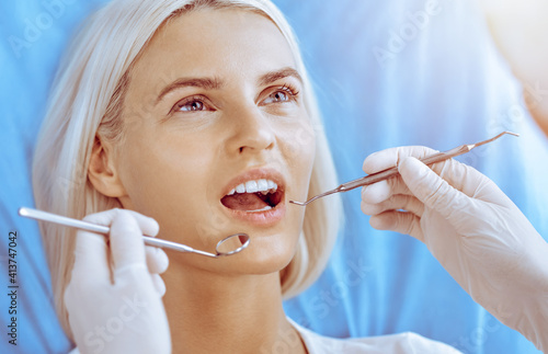 Smiling blonde woman examined by dentist at dental clinic. Healthy teeth in medicine concept