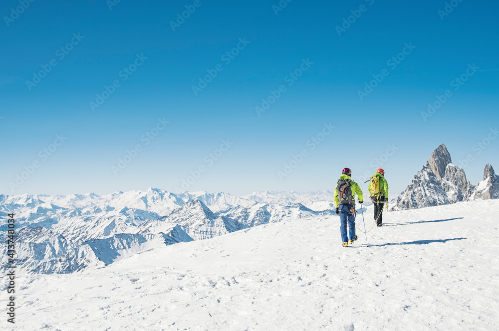 Rear view of hikers walking on snow covered mountain against clear blue sky Rear view of hikers walking on snow covered mountain against clear blue sky