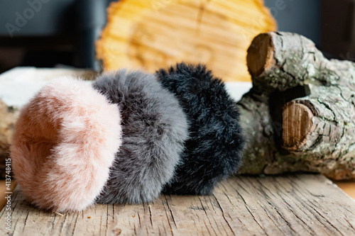 Fashionable and stylish fur elastic bands for hair and hairstyles. Multi-colored artificial and natural cannons on a natural wooden background